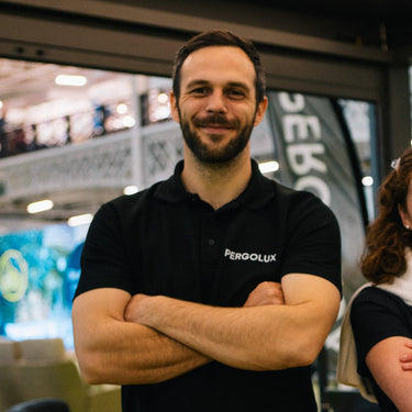 PERGOLUX customer service representative wearing a black PERGOLUX shirt with arms crossed in an indoor setting