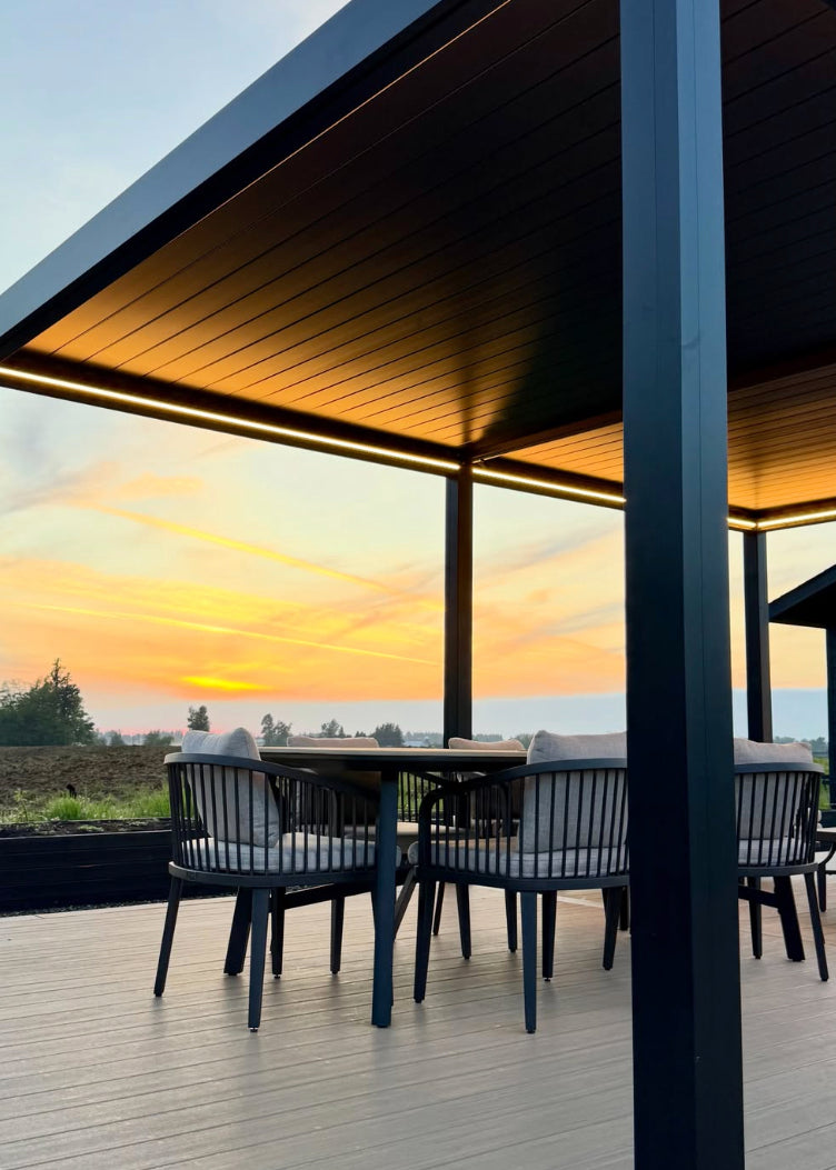 Modern louvered aluminum pergola with integrated LED strip lighting over an outdoor dining space at sunset