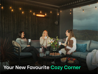 Women smiling and enjoying hot beverages under pergola with heater. Text says " Your New Favourite Cozy Corner"