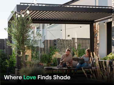 man with drink sitting next to woman with computer on couch under pergola next to tree. Text says "Where Love Finds Shade".