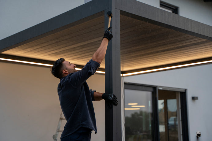 Person installing or adjusting a metal pergola on a building exterior.