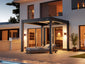 A modern, motorized PERGOLUX Skydance pergola with integrated lighting, covering a patio area with a cozy outdoor seating arrangement visible in the background.