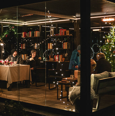 People sitting at a table in a cozy indoor setting with Christmas decorations.