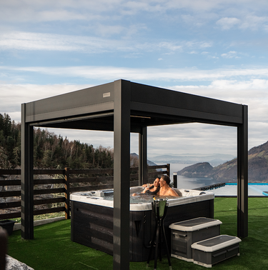 Hot tub with a modern black pergola overlooking a scenic landscape